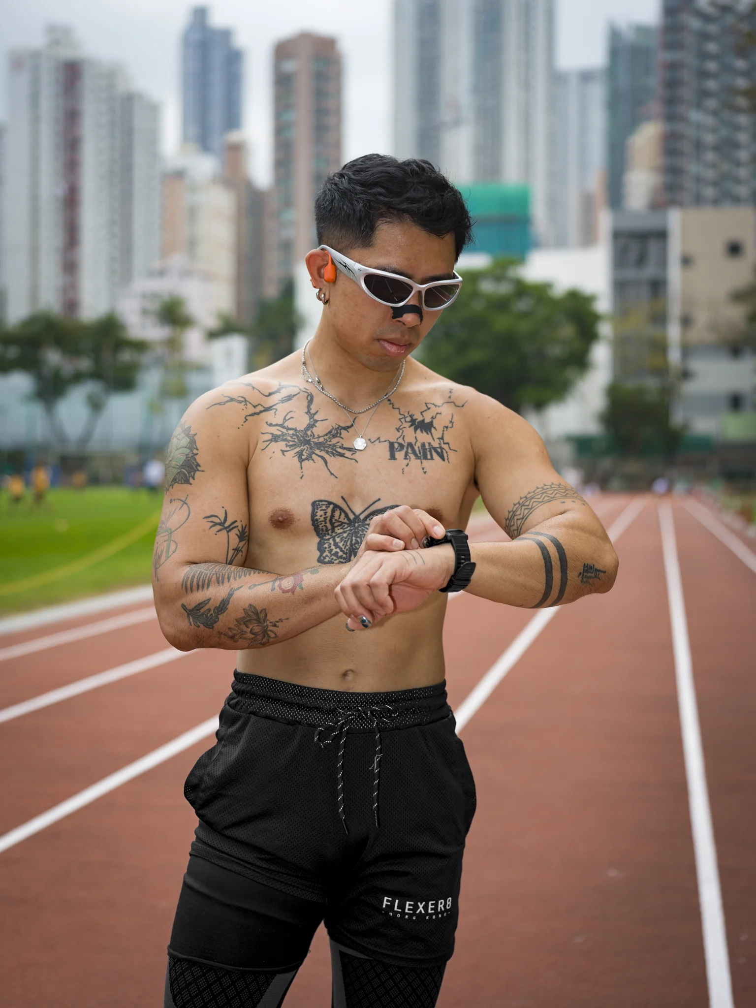 Michael checks his watch on a running track with Hong Kong towers behind him
