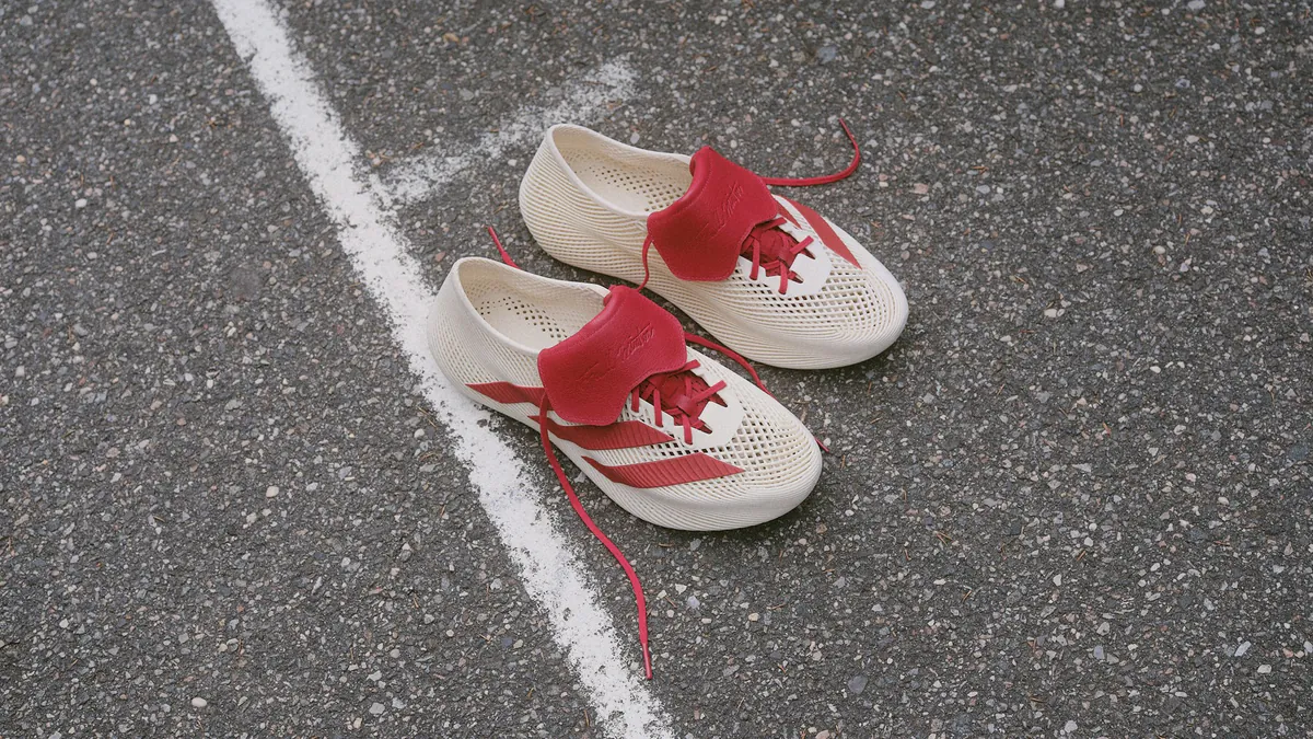 Cream adidas x Tyrrell Winston CLIMACOOL shoes with red folded tongues and stripes on an outdoor court.