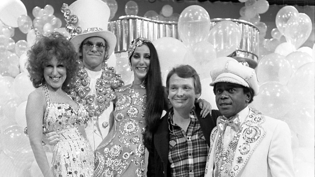 Bette Midler, Elton John, Cher, Bob Mackie, and Flip Wilson pose together in sparkling performance clothes in 1975.