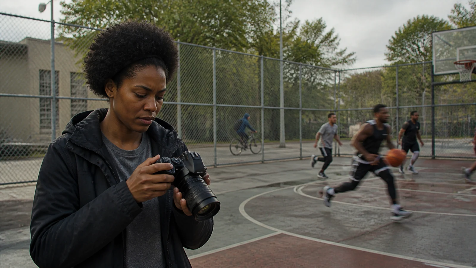 Hands adjusting the mode dial of an unbranded mirrorless camera in changing outdoor light