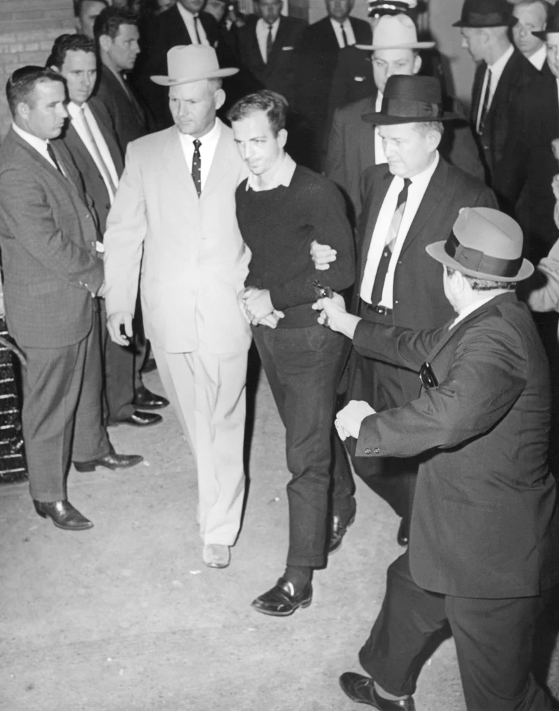 Jack Beers’s elevated black-and-white view shows Jack Ruby extending a revolver toward an upright Lee Harvey Oswald, flanked by detectives, just before the later Jackson frame.