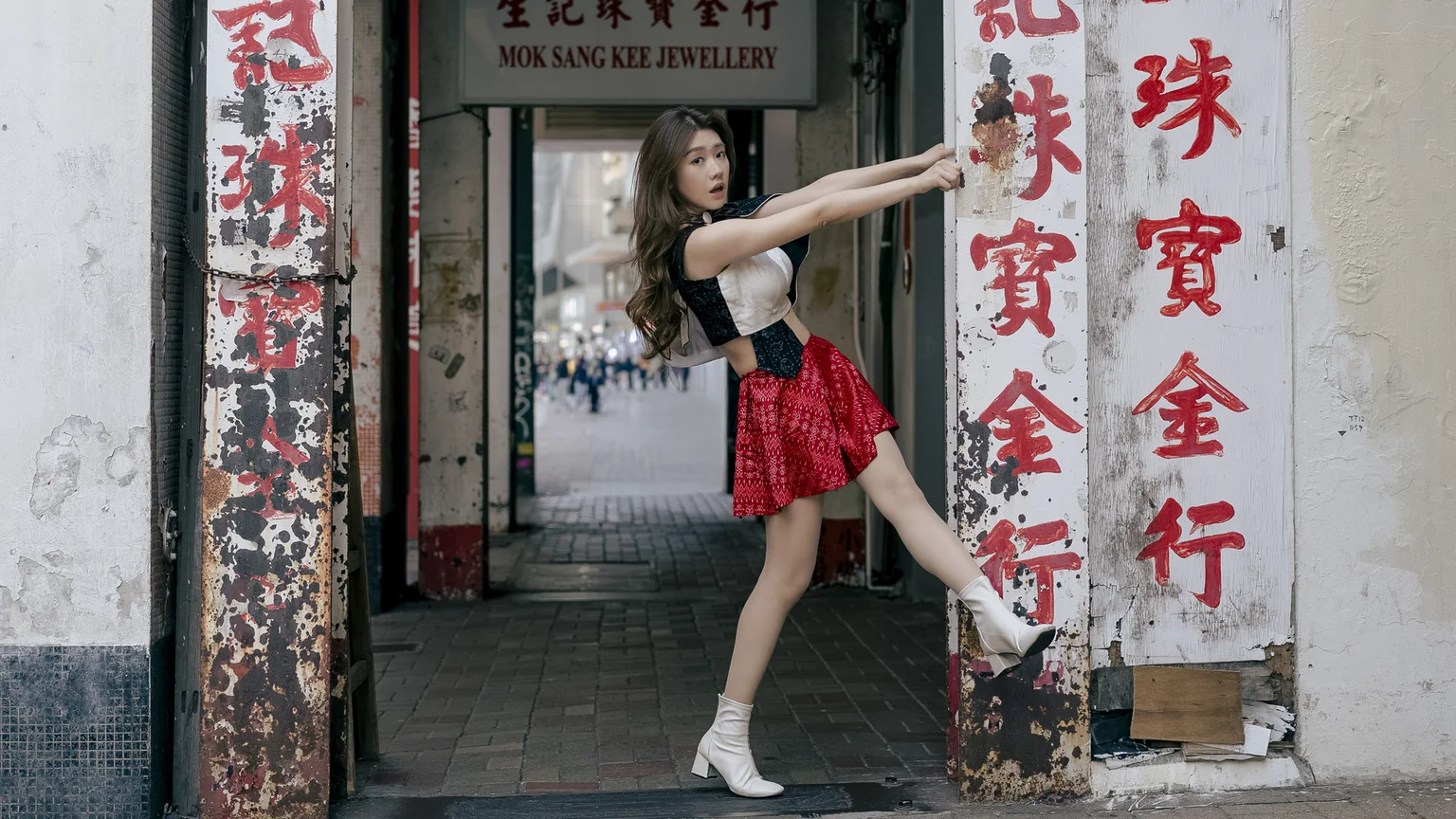 Ivy Liu leans into a weathered Hong Kong shopfront framed by red Chinese signs