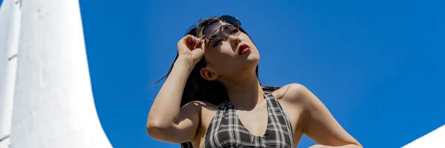 Fashion model in sunglasses framed by blue sky and white architecture