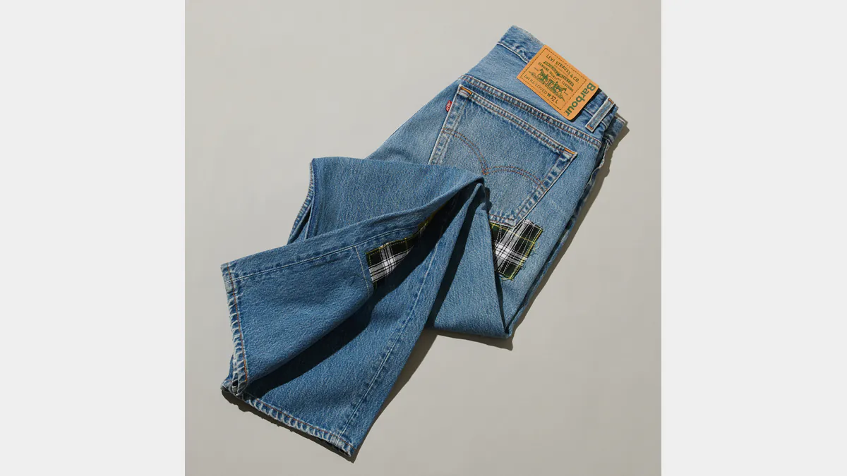 Folded Levi’s and Barbour Re-Loved jeans with a checked fabric insert and collaboration patch.