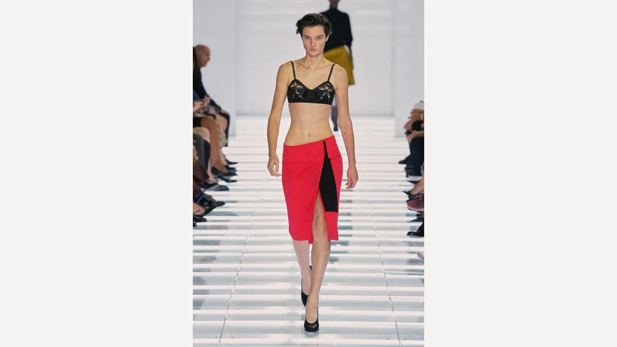 Model on the Prada Spring/Summer 2027 Milan runway in a black lace top and red skirt.