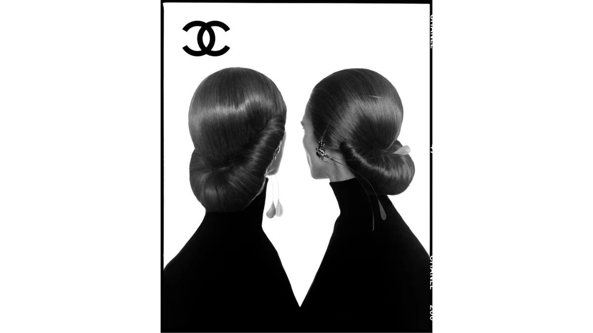 David Bailey’s official Chanel Spring/Summer 2027 show teaser photograph, showing two dark profiles with sculpted hairstyles against a white ground.