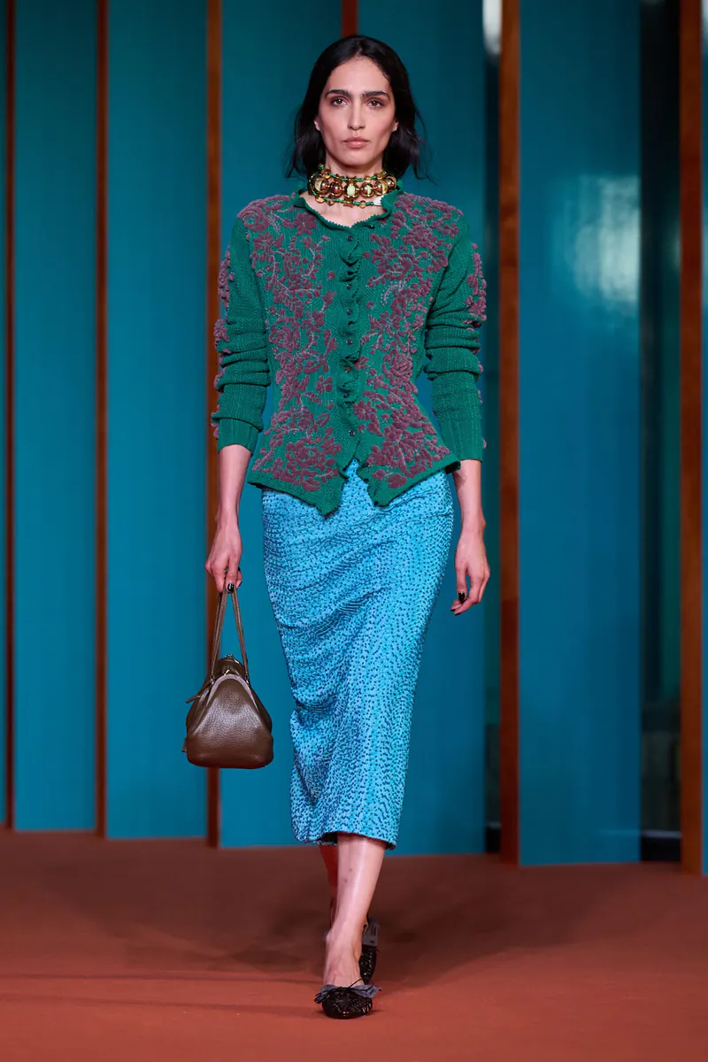 Model in a green embroidered cardigan and blue skirt on the Tory Burch Spring 2027 runway.