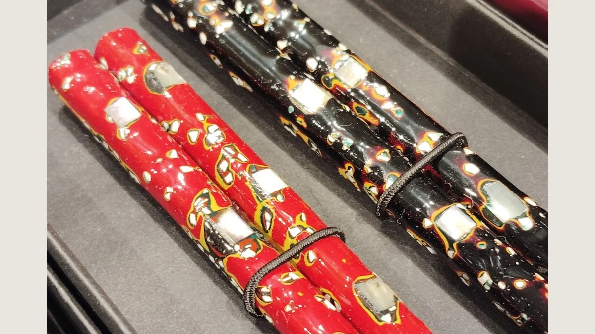 Red and black Wakasa lacquered chopsticks with pale shell fragments and fine speckled patterns, shown with a neutral matte.